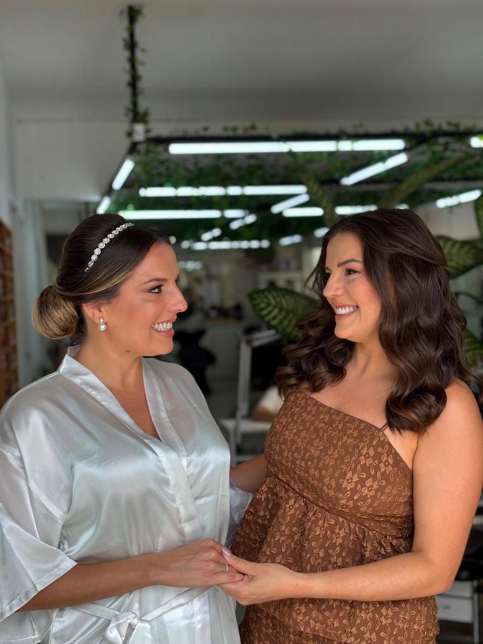 Noiva de roupão sorrindo com uma convidada